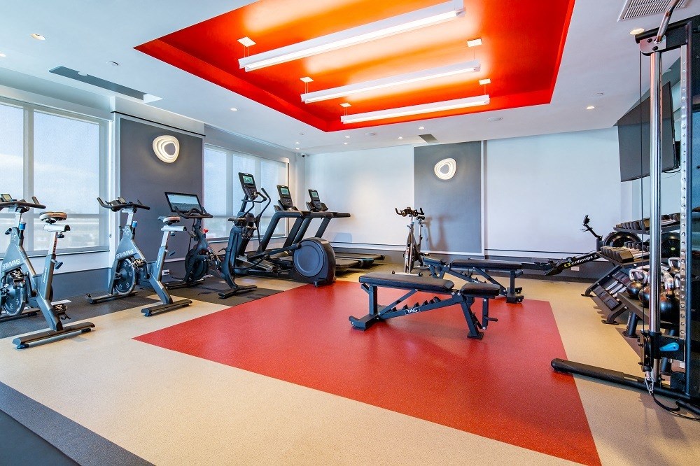 a gym with various exercise machines and weights on a red floor