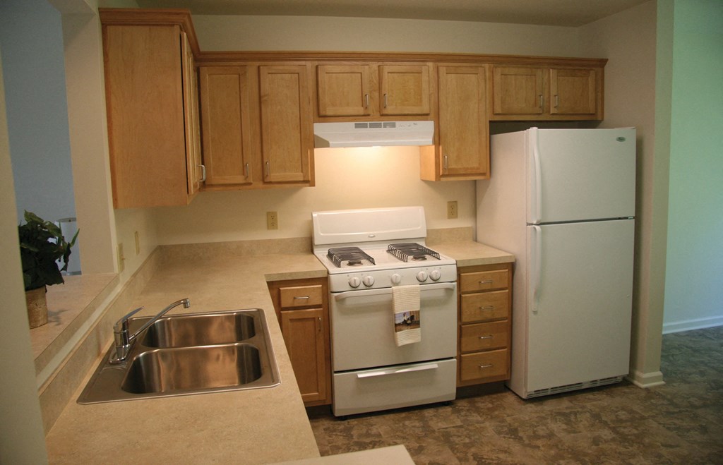 an empty kitchen with white appliances and wooden cabinets