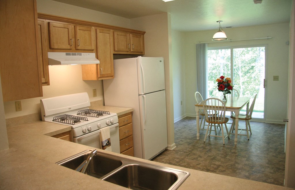 A kitchen with a white refrigerator, stove, and sink.