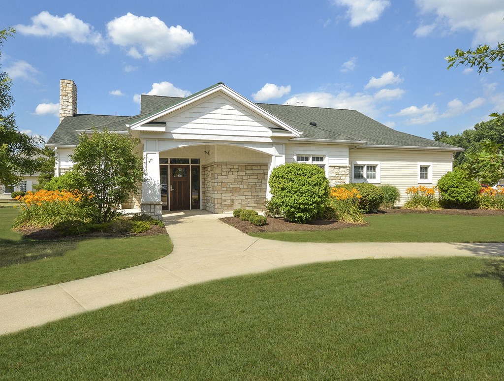 A white house with a grey roof and a stone pillar in front.