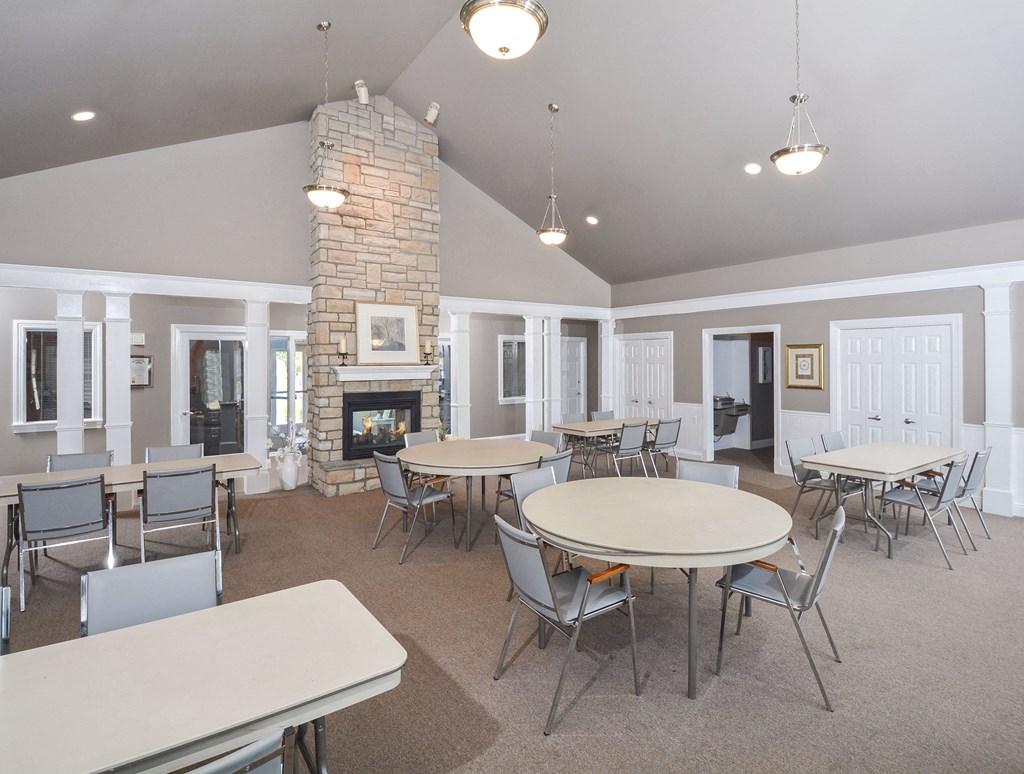 A spacious room with a stone fireplace and multiple tables and chairs.