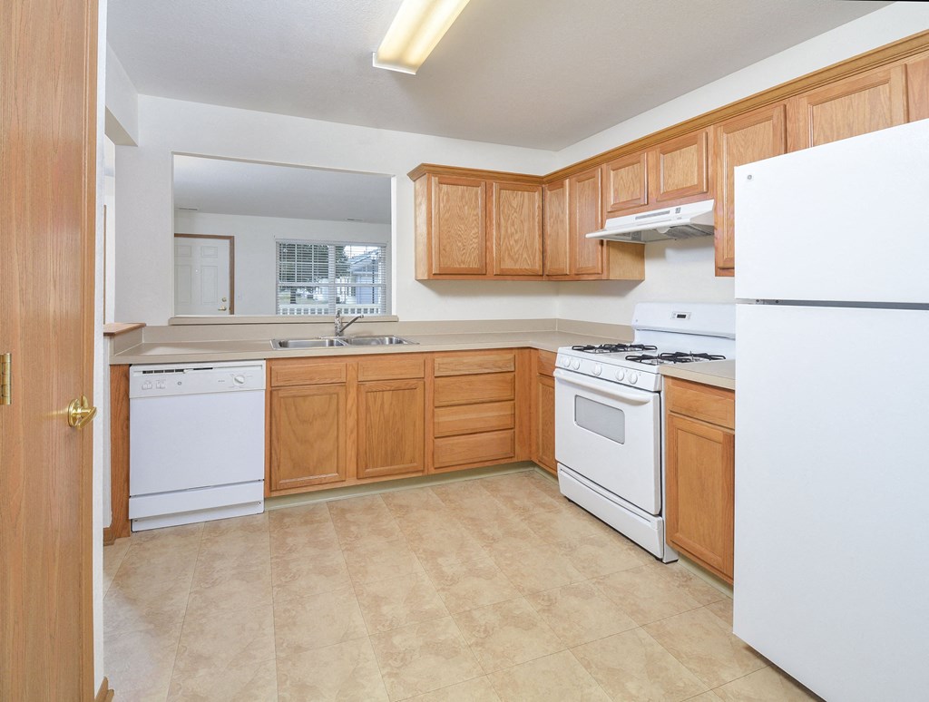A kitchen with wooden cabinets and white appliances.