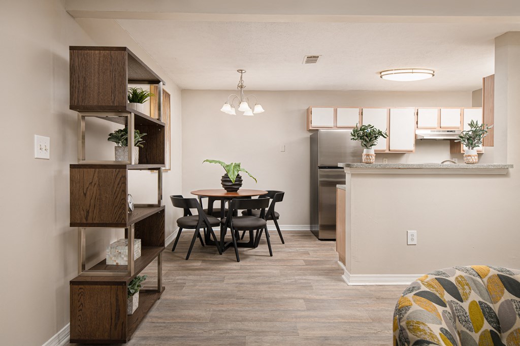 a dining area with a table and chairs and a kitchen in the background