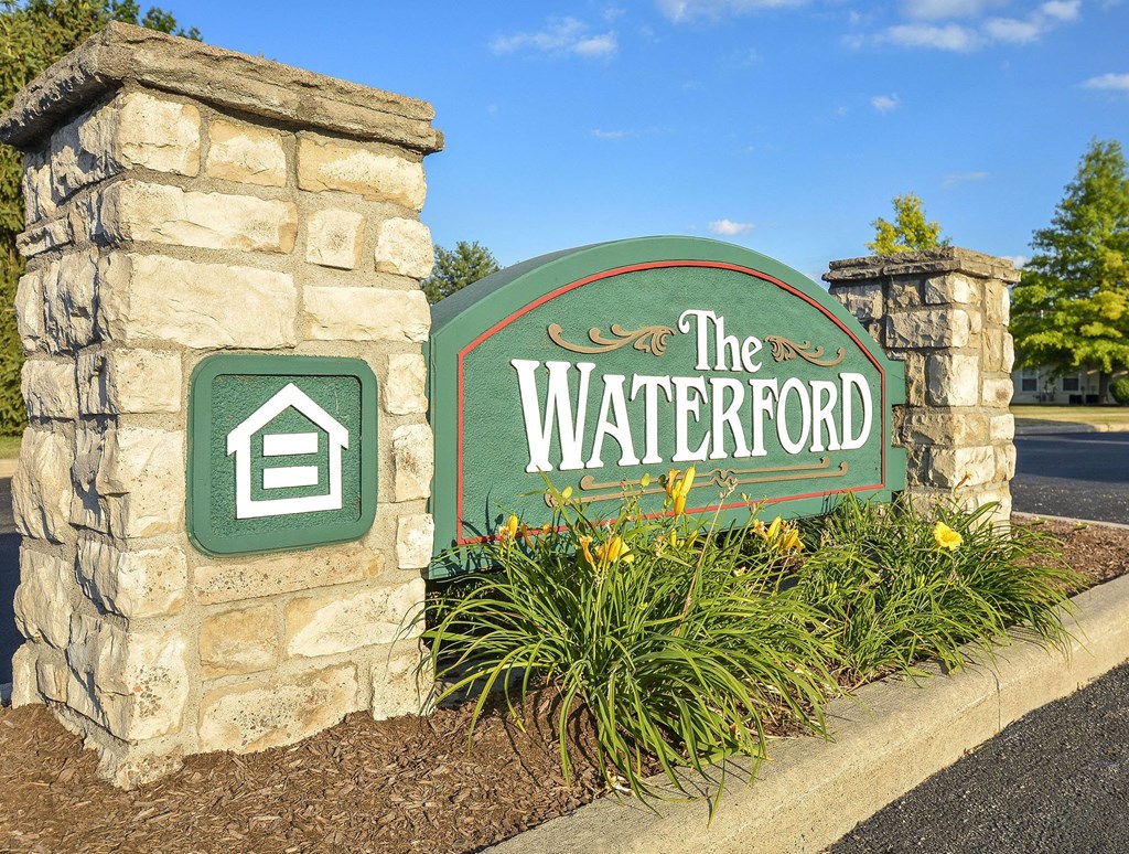 A sign for The Waterford is displayed in front of a stone pillar.