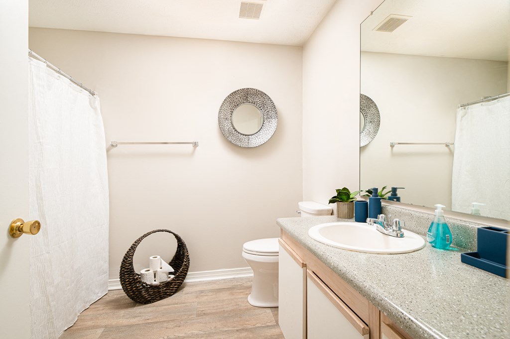 a bathroom with a white shower curtain and a white toilet next to a sink with a mirror