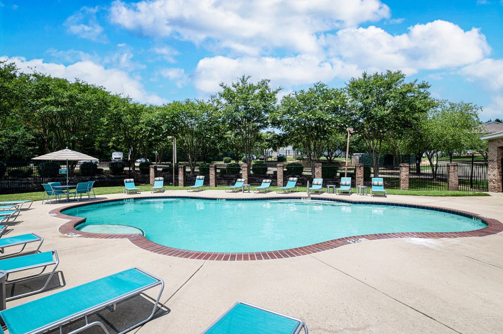 a resort style pool with chaise lounge chairs and trees in the background