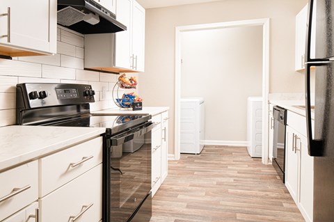 a kitchen with white cabinets and black appliances and a wood floor