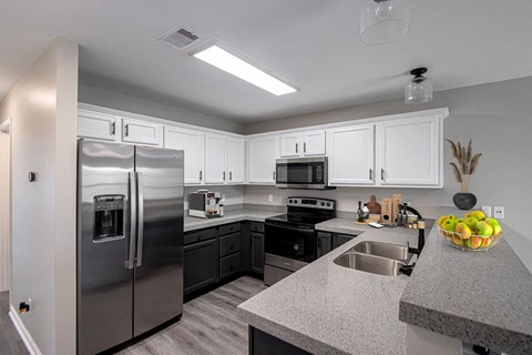 A modern kitchen with a stainless steel refrigerator and black cabinets.