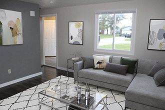 Living room with a gray couch and a glass coffee table at Evergreen Village Townhomes, Lorain, OH 44053
