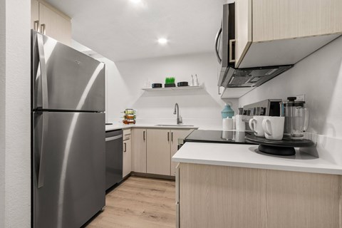 A modern kitchen with a stainless steel refrigerator and wooden cabinets.