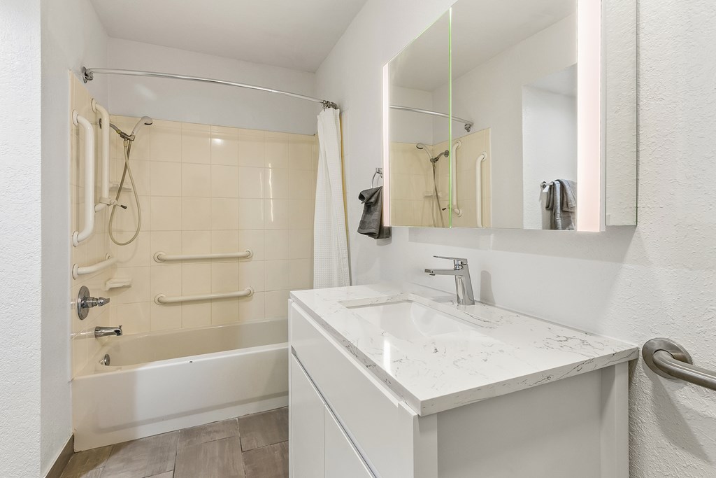 A white bathroom with a tub, sink, and mirror.