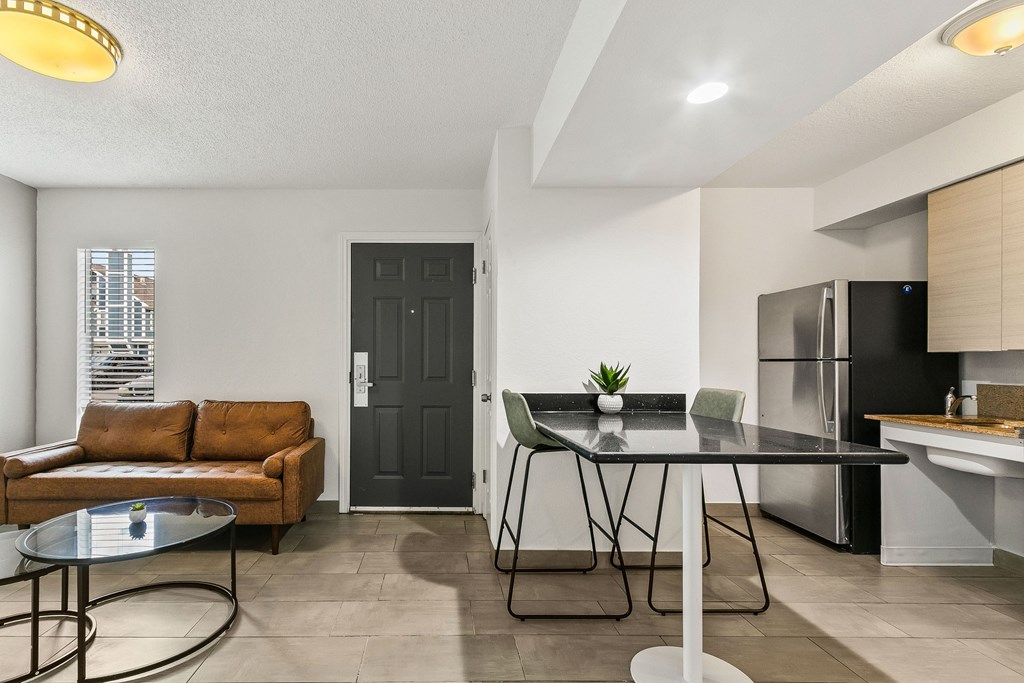 A modern kitchen with a black fridge and a dining table with four chairs.