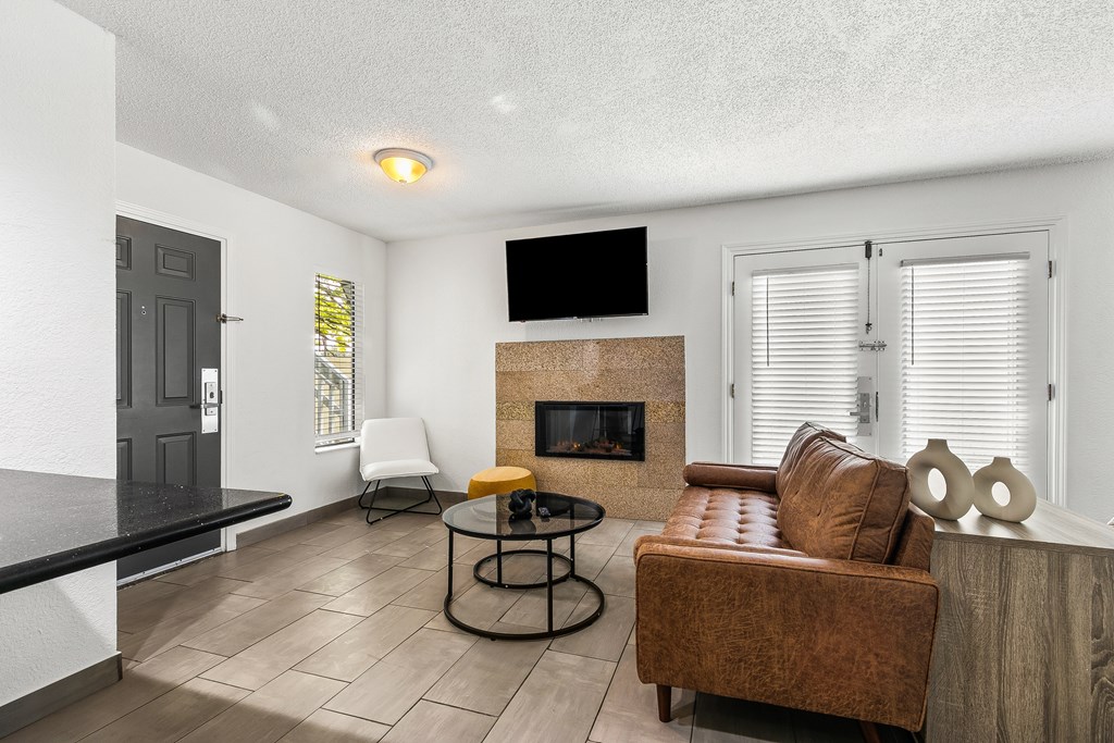 A living room with a brown leather couch, a black coffee table, and a fireplace.