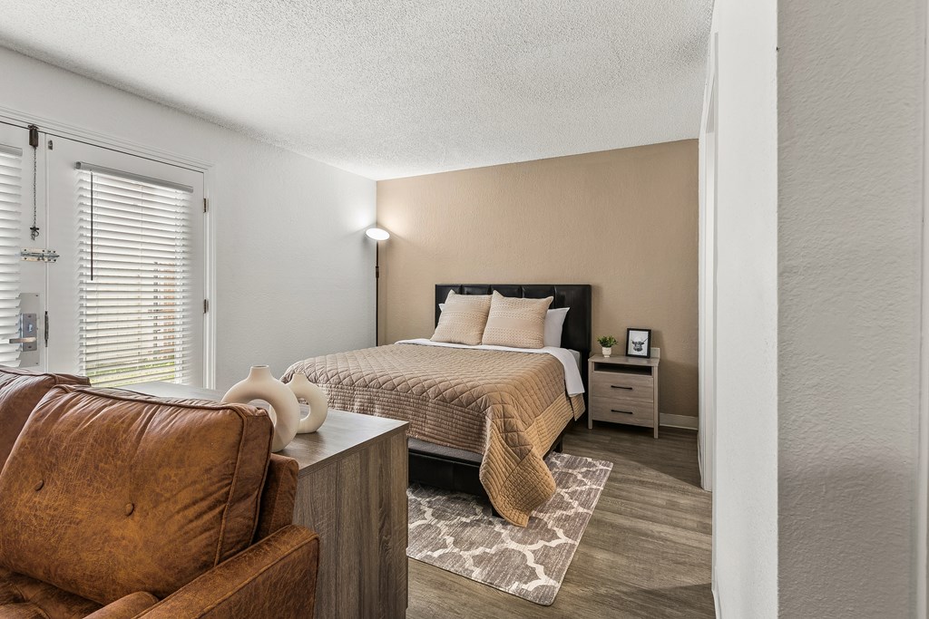 A bedroom with a bed, nightstand, and chair.