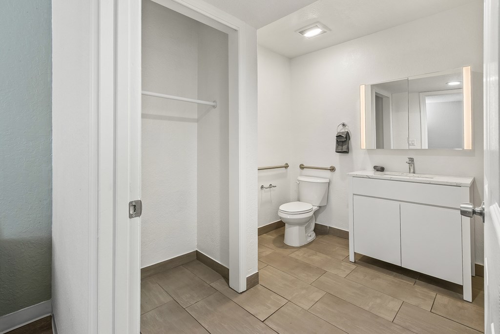 A white bathroom with a toilet, sink, and mirror.