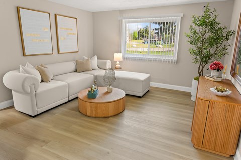 A living room with a white couch, a wooden coffee table, and a plant.