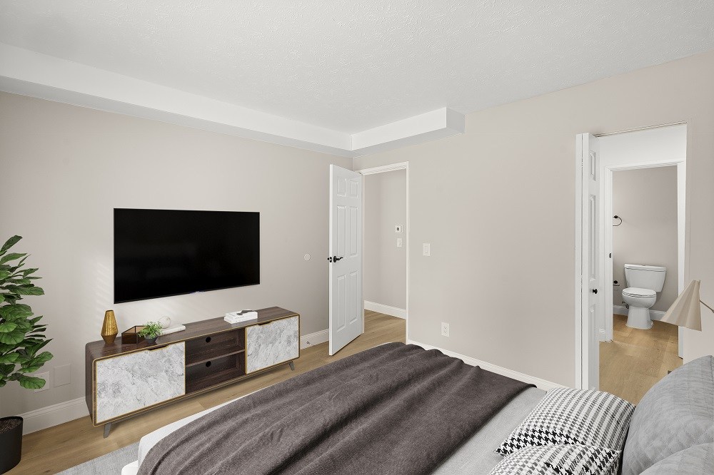 A bedroom with a large bed and a flat screen TV mounted on the wall.
