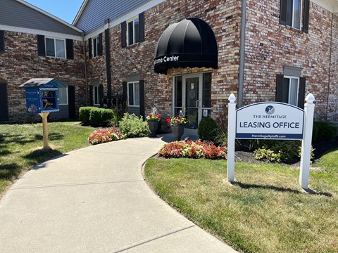 A sign for The Hermitage Leasing Office is in front of a brick building.