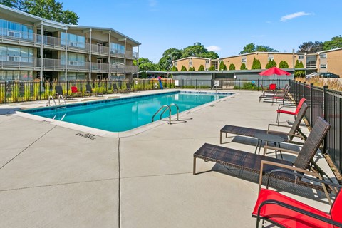 A swimming pool surrounded by lounge chairs and umbrellas.