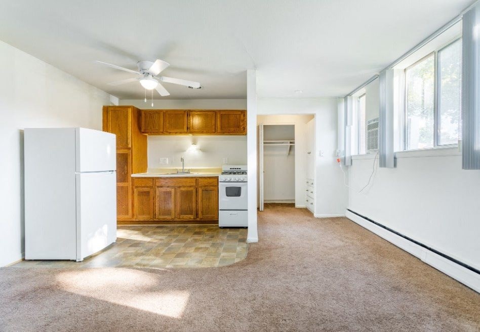 an empty kitchen with white appliances and wood cabinets