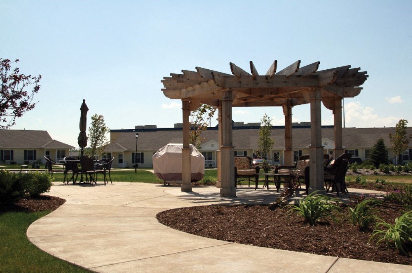 a patio with a wooden gazebo and tables and chairs
