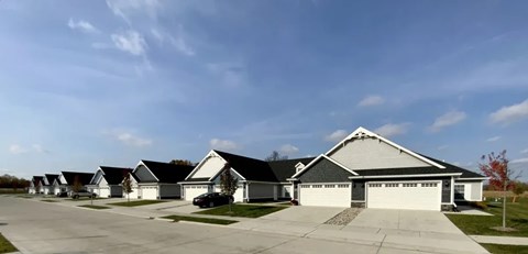 A row of houses with a car parked in front of the first one.