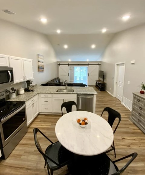 A kitchen with a table and chairs in the foreground and a living room in the background.