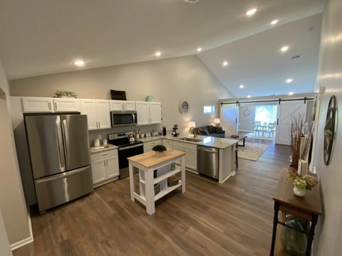 A kitchen with a refrigerator, microwave, oven, and sink.