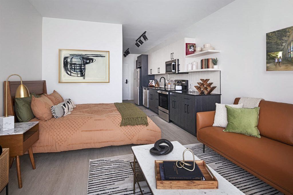 a living room with a bed and a kitchen