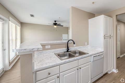 A kitchen with a marble countertop and white cabinets.