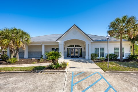 A white building with a black roof and a parking lot in front.