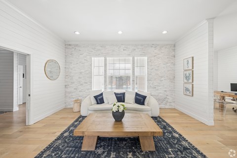 A living room with a white brick wall and a wooden coffee table.