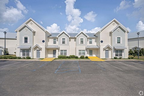A large white building with a parking lot in front.