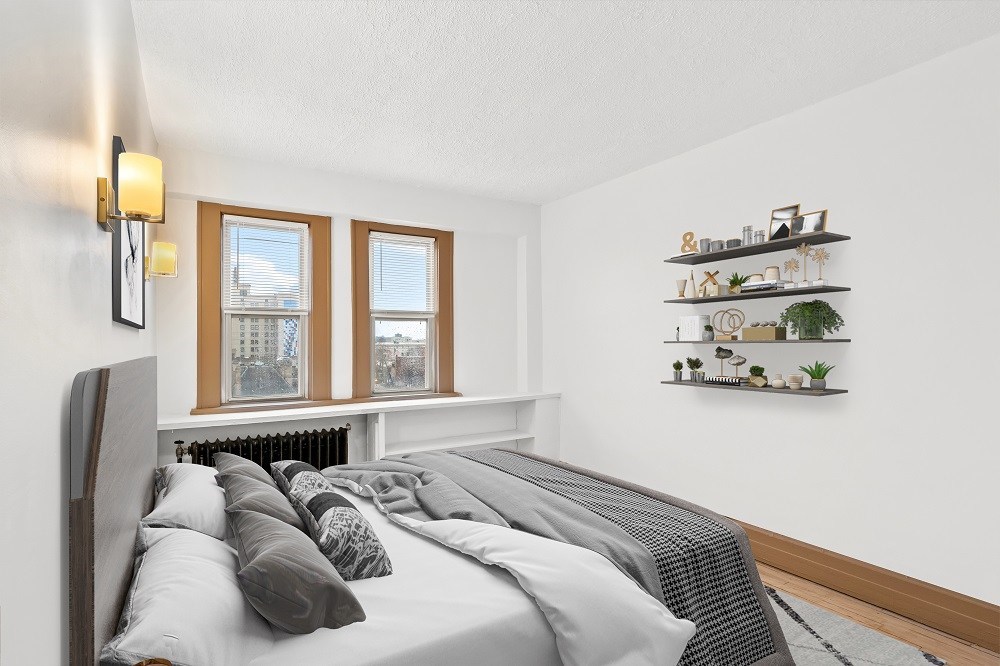 A bedroom with a bed, pillows, a window, and a shelf with plants and decorations.