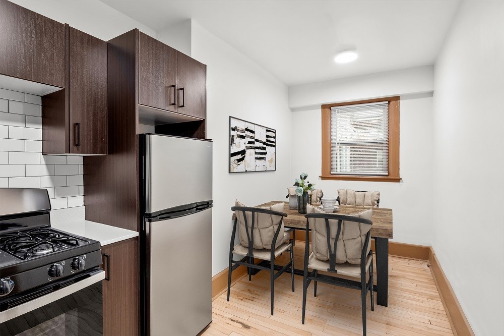 A kitchen with a stove, refrigerator, and dining table.