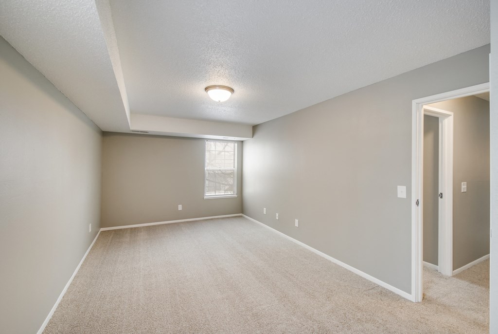 A spacious room with a carpeted floor and a window.