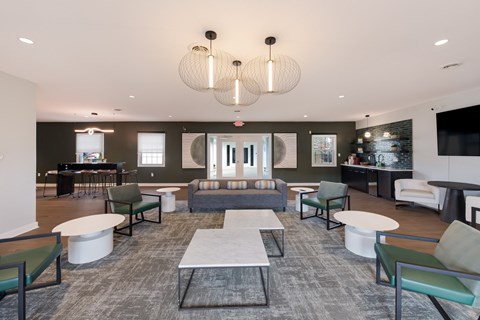 A spacious room with a grey carpet and a variety of seating options.