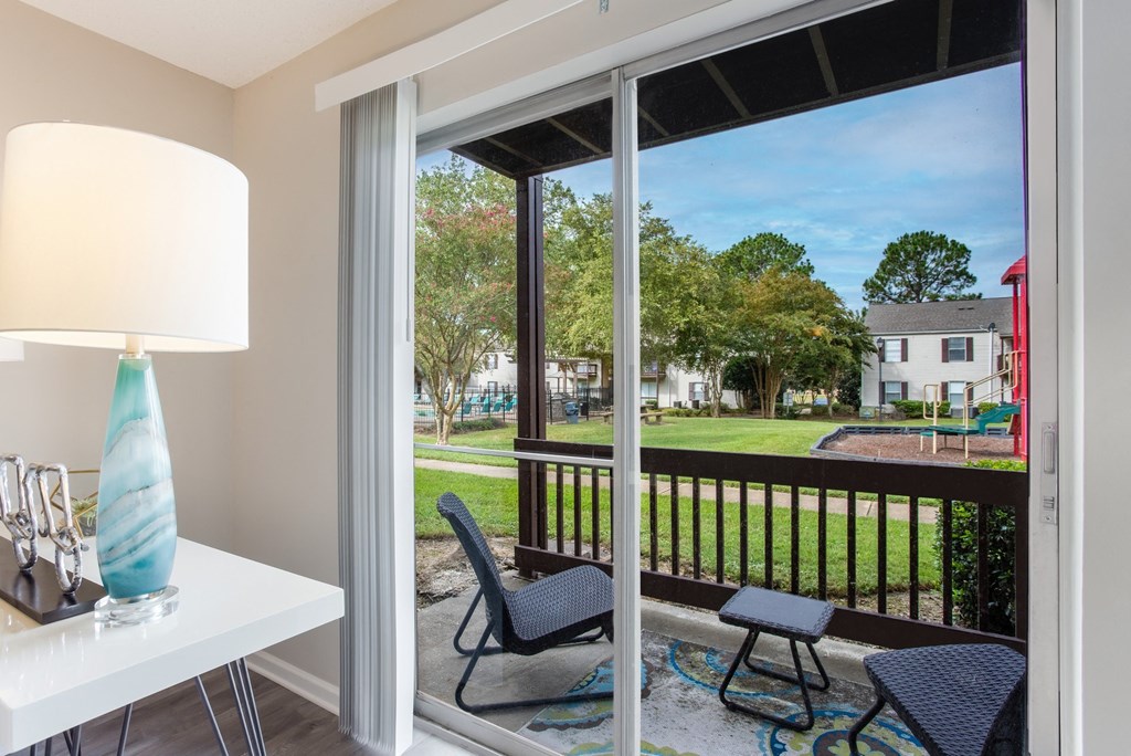 a balcony with a view of a yard and a table with chairs