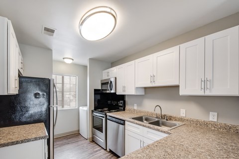 A kitchen with white cabinets and a black fridge.