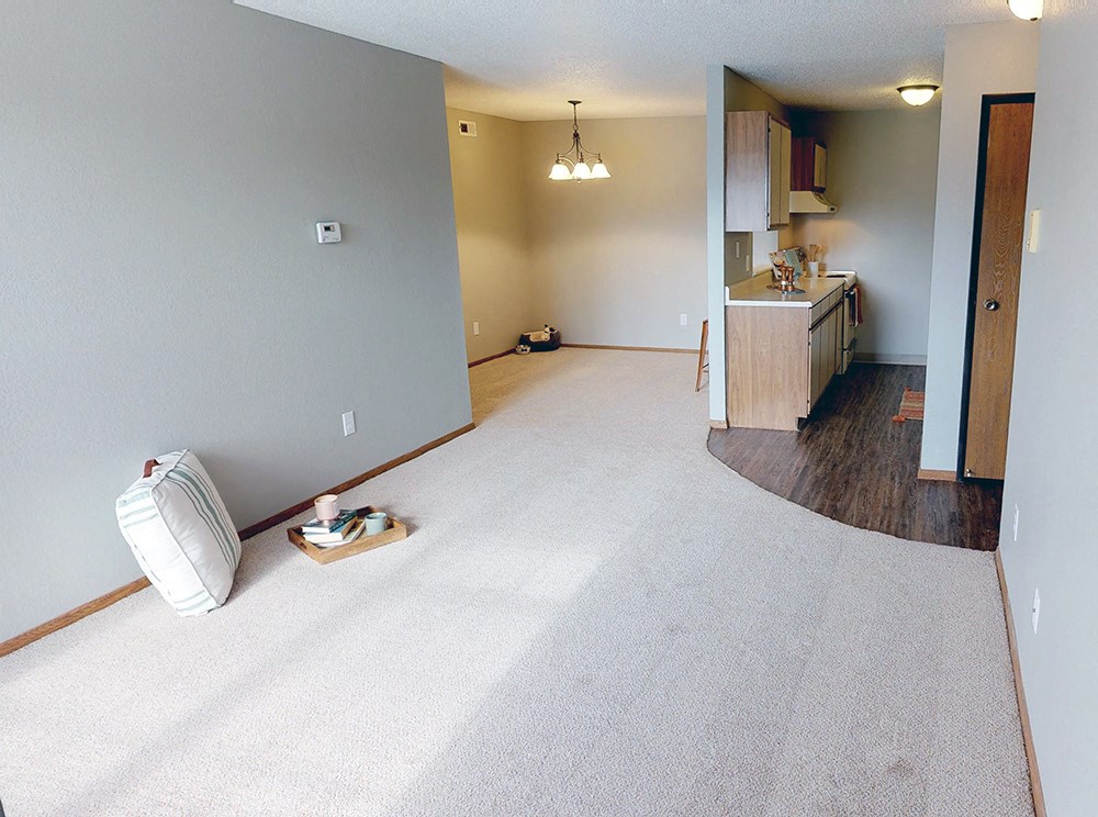 A white pillow and a white bag are on the floor of a room.