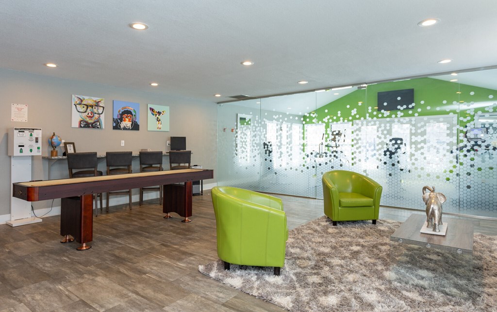 A room with a long table and green chairs.