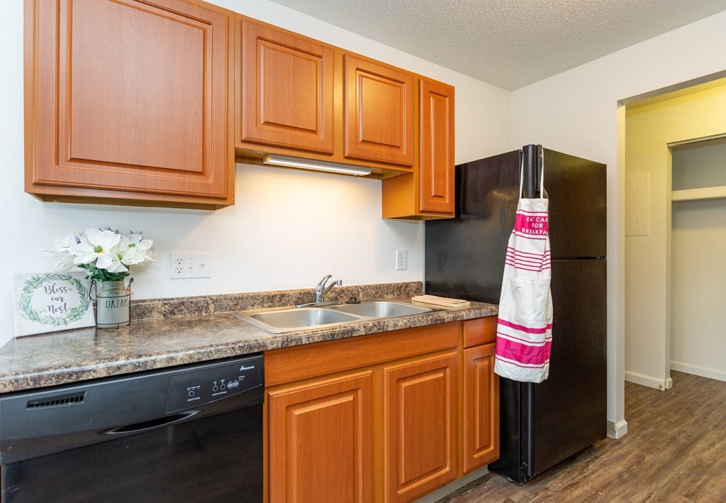 A kitchen with wooden cabinets and a black refrigerator.