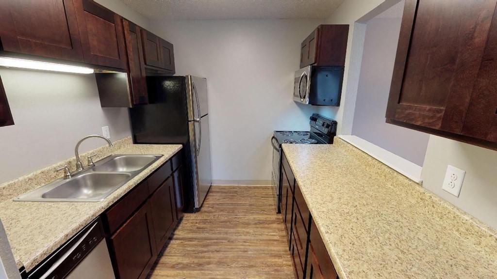 A kitchen with brown cabinets and a black refrigerator.