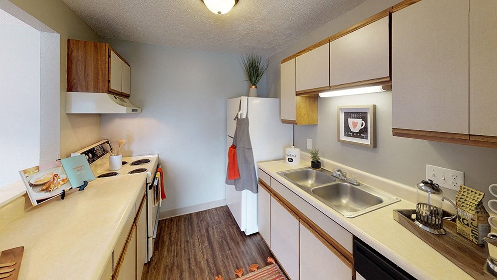 A kitchen with a stove, sink, and cabinets.