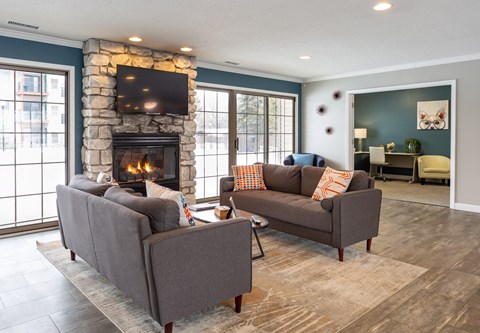A living room with a stone fireplace and two grey couches.