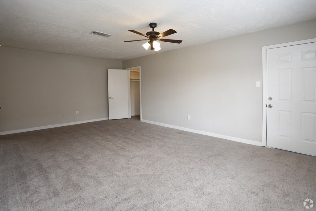 an empty living room with a ceiling fan