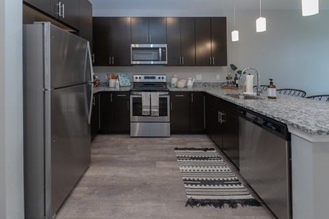 A modern kitchen with a stainless steel refrigerator and black cabinets.