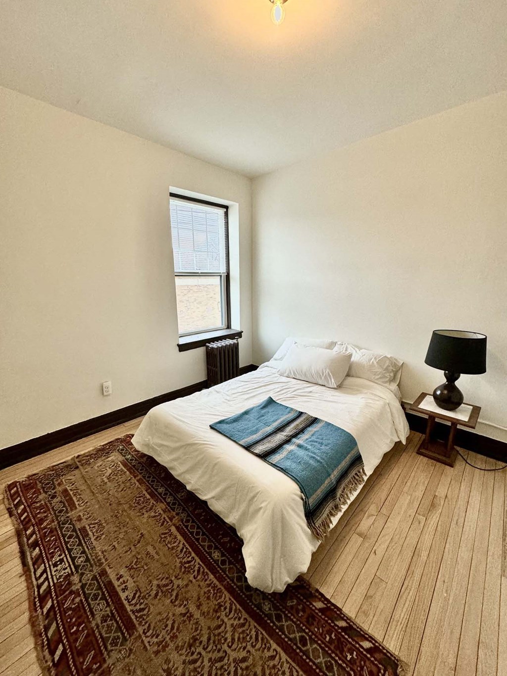 a bedroom with a bed and a rug and a window