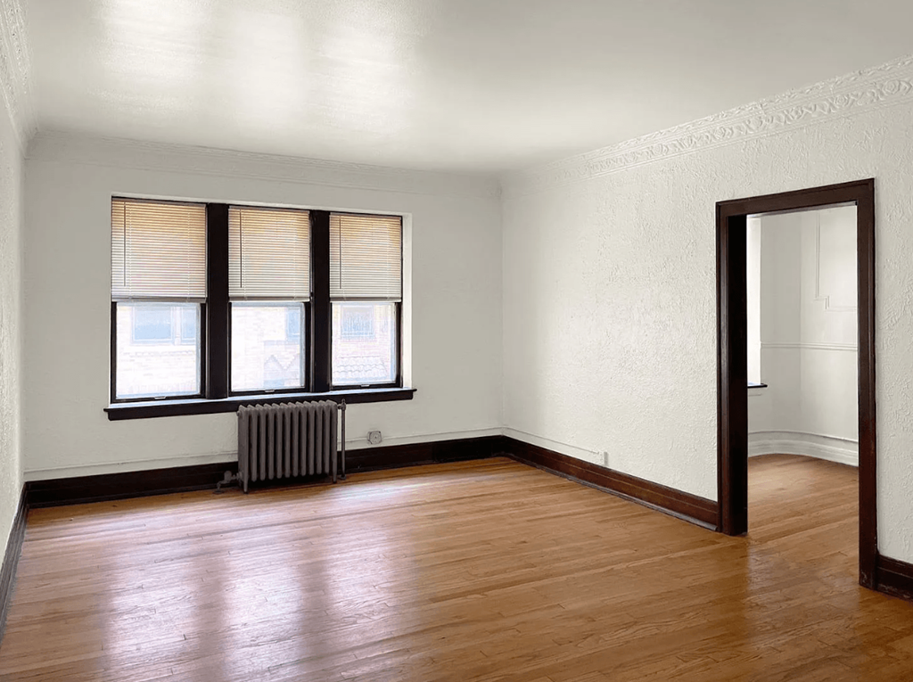 an empty living room with wood floors and a window