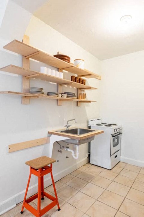 A kitchen with a white oven and a wooden shelf above the counter.